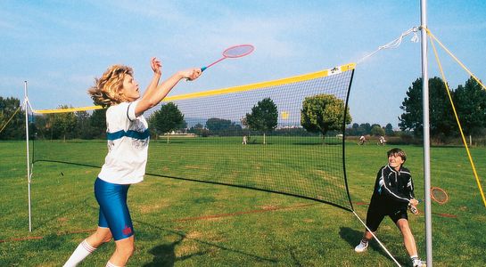 Freizeit-Badmintonnetz mir 2 Spielerinnen auf Rasen
